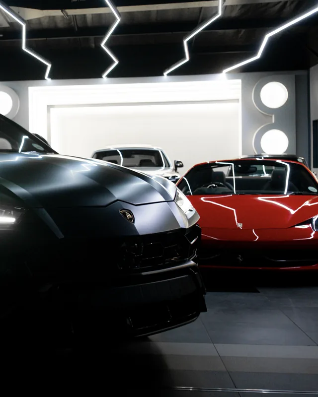 Matte grey Lamborghini Urus in the showroom beside a red Ferrari