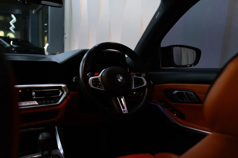 BMW interior with an M steering wheel, carbon trim and orange leather door panel and seat