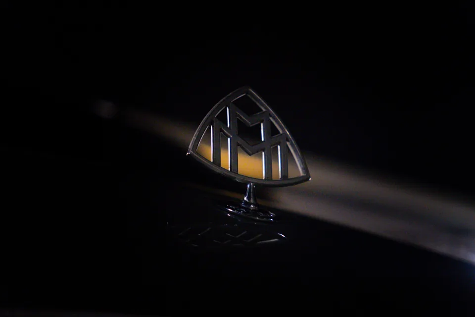 Illuminated Maybach emblem standing on a bonnet against a black background