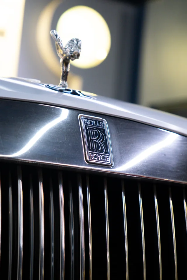 Spirit of Ecstasy mascot above a silver Rolls-Royce bonnet, with the RR badge and polished vertical grille below