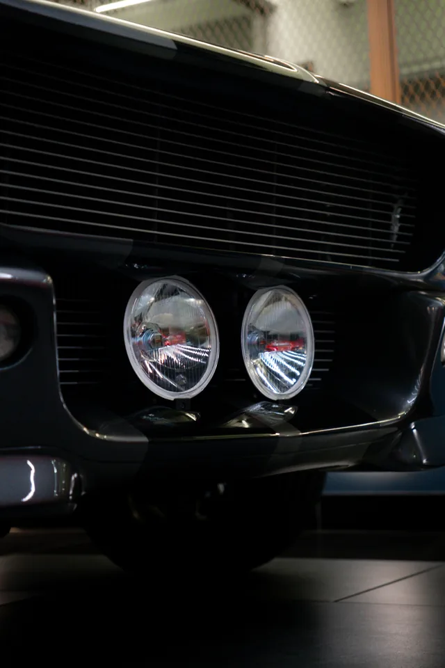 Twin round driving lights in the grille of a dark 1967 Shelby GT500, photographed close up